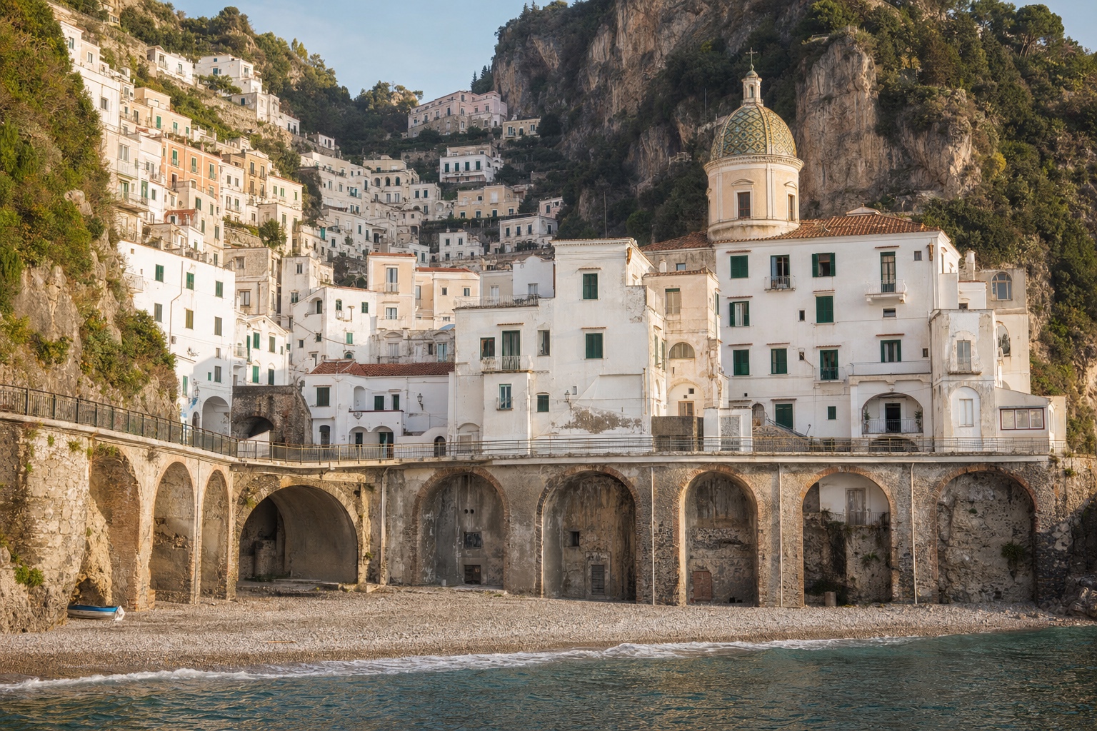 Verschachtelte Häuser von Atrani mit Viadukt und Kirchenkuppel über dem kleinen Strand