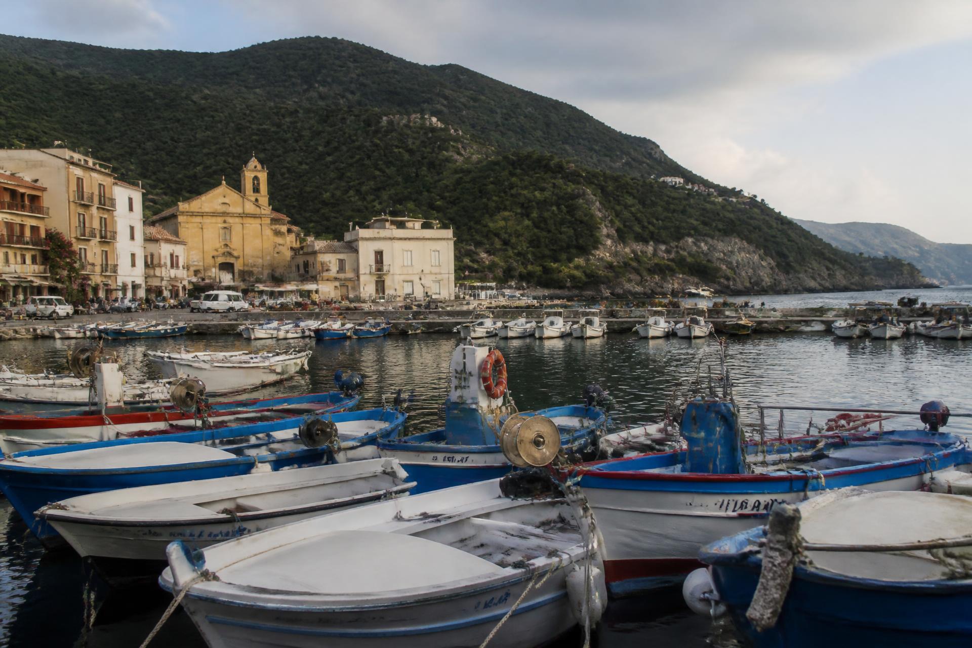 Fischerboote im Hafen von Marina di Camerota, dahinter Kirche und bewaldete Hügel des Cilento